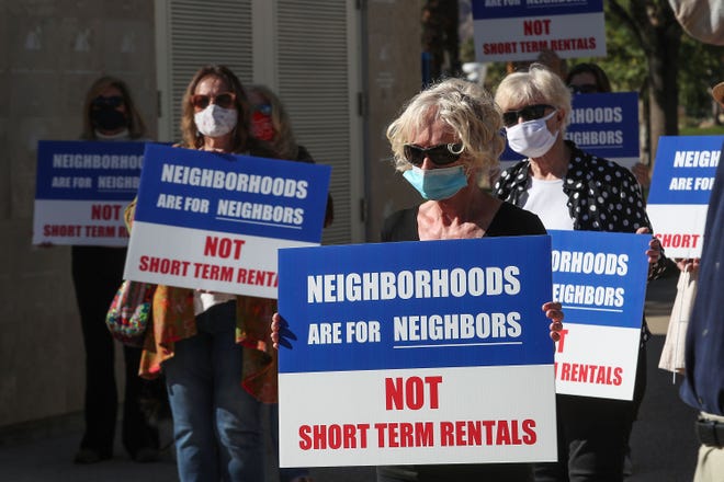 La Quinta residents who want the city to limit the number of short term vacation rentals hold signs during a press conference at La Quinta City Hall, January 12, 2021.